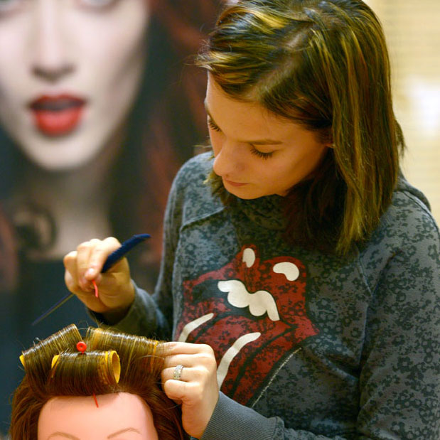 Junge Frau wickelt Lockenwickler auf das Haar